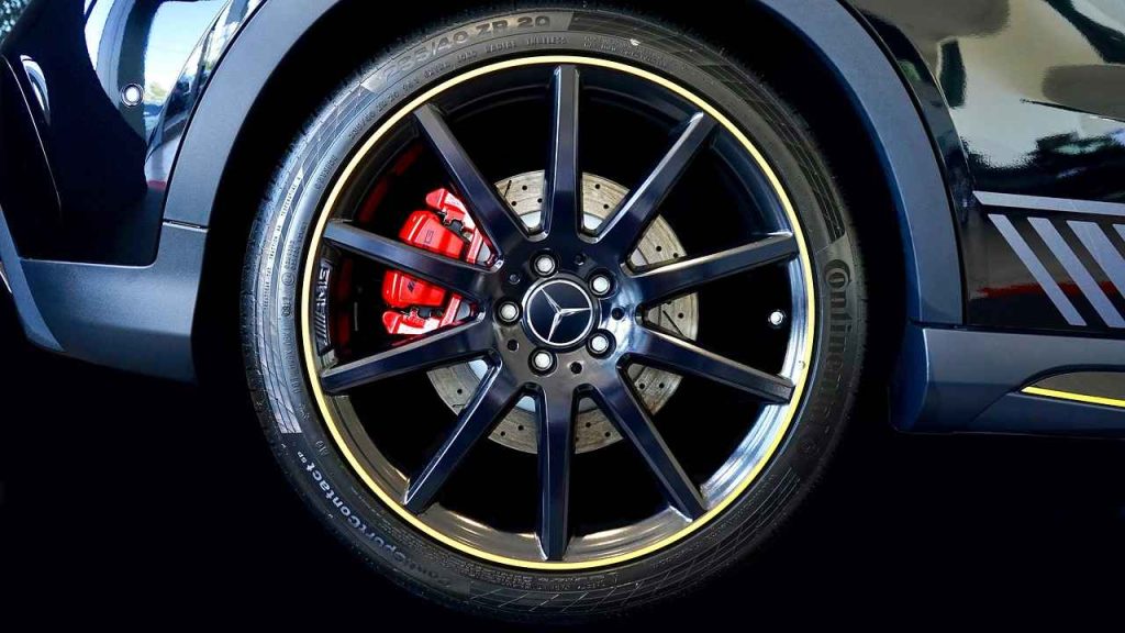 A close-up of a black sports car wheel featuring yellow spokes and a sleek tyre design.