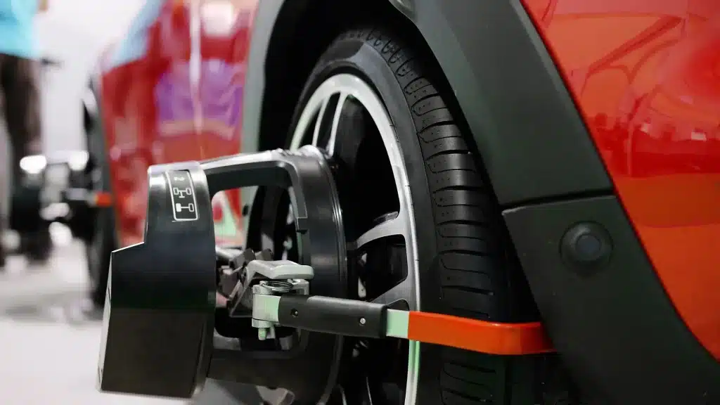 A mechanic repairs a car tire, focusing on wheel alignment adjustments.