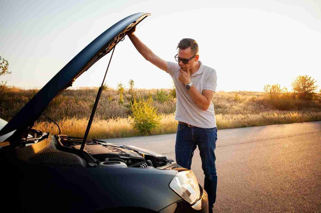 A man inspects his car's engine, seeking solutions for a breakdown on Belt Line Road in Desoto, TX.